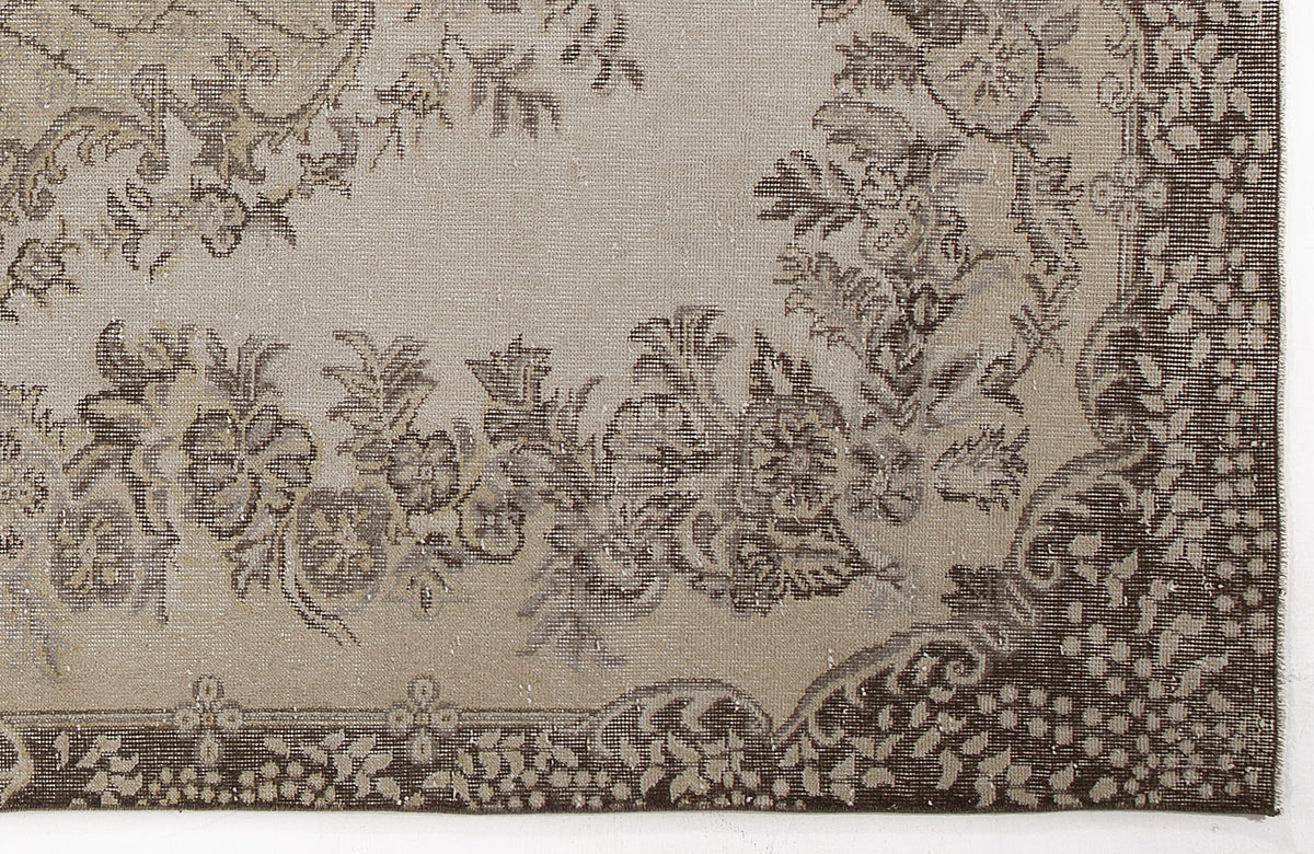Taupe and dark brown rug with a distressed floral medallion pattern and a detailed decorative border.