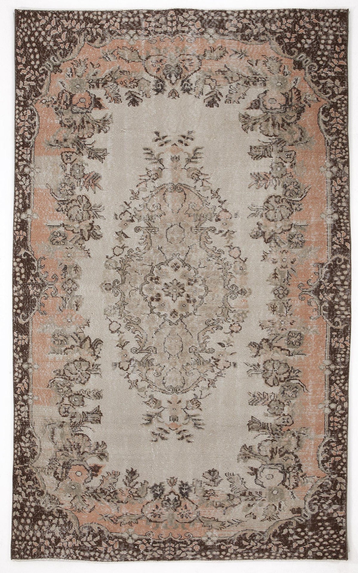 Distressed beige, brown, and muted peach rug with a central floral medallion and ornate botanical border.