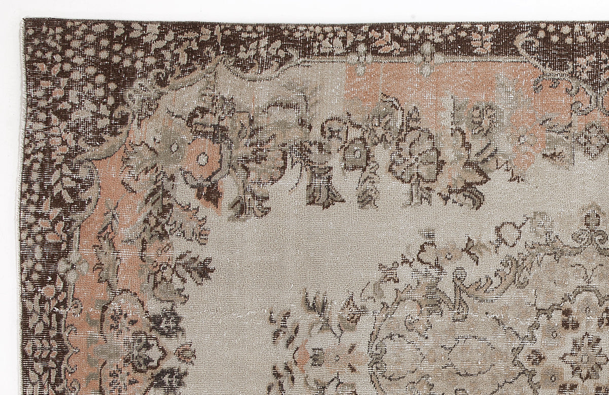 Distressed beige, brown, and muted peach rug with a traditional floral medallion pattern and ornate border.