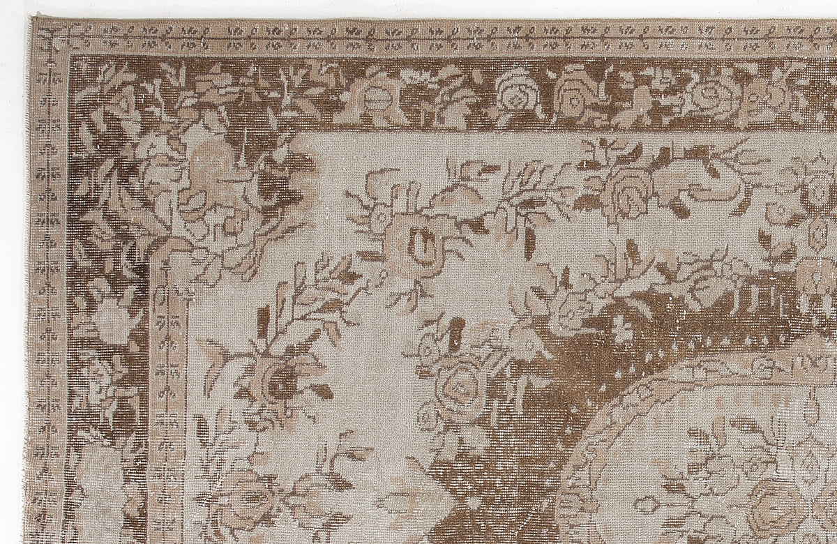 Beige and brown traditional rug with a distressed floral medallion pattern and ornate border.