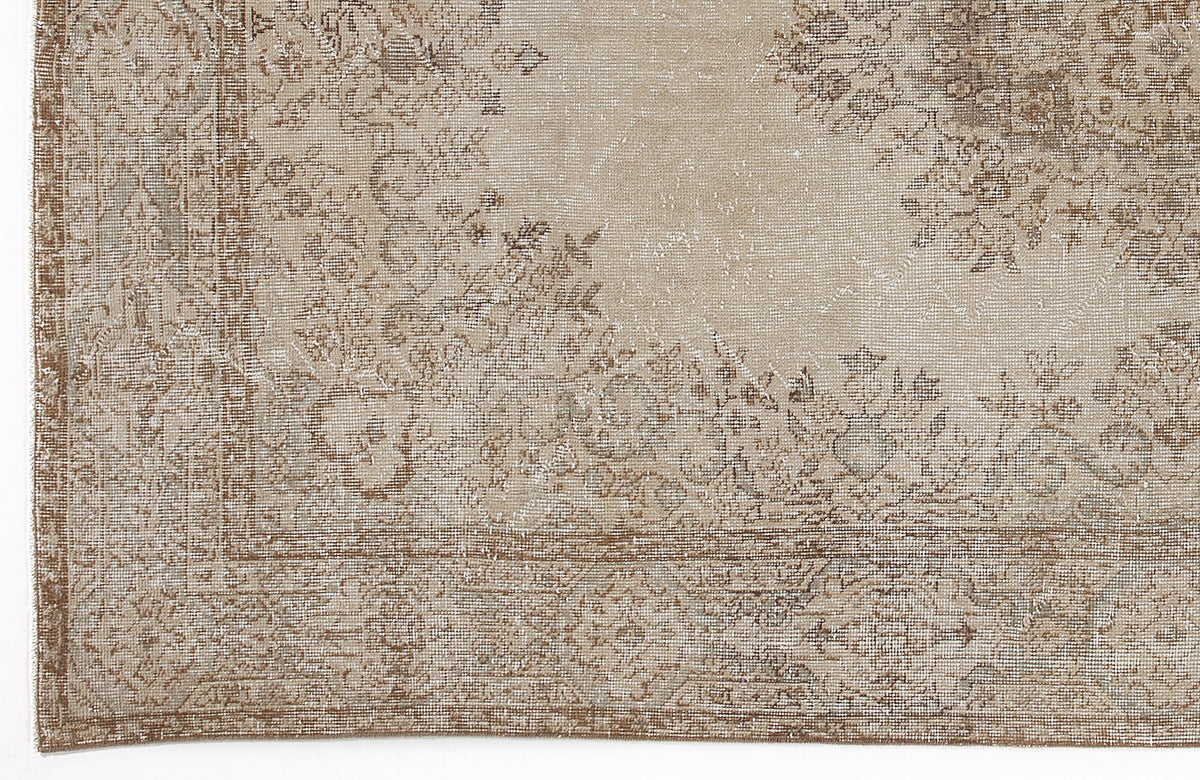 Beige and taupe distressed rug with a faded traditional floral medallion pattern and a decorative border.