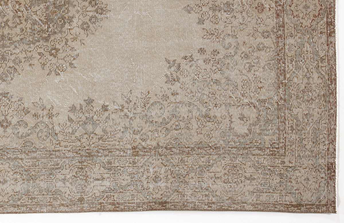 Beige and brown distressed traditional rug with a faded floral medallion pattern.