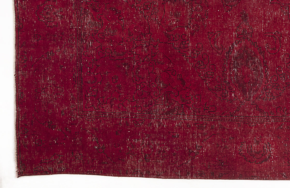 Deep red vintage-style rug with a faded black floral medallion pattern and distressed texture.