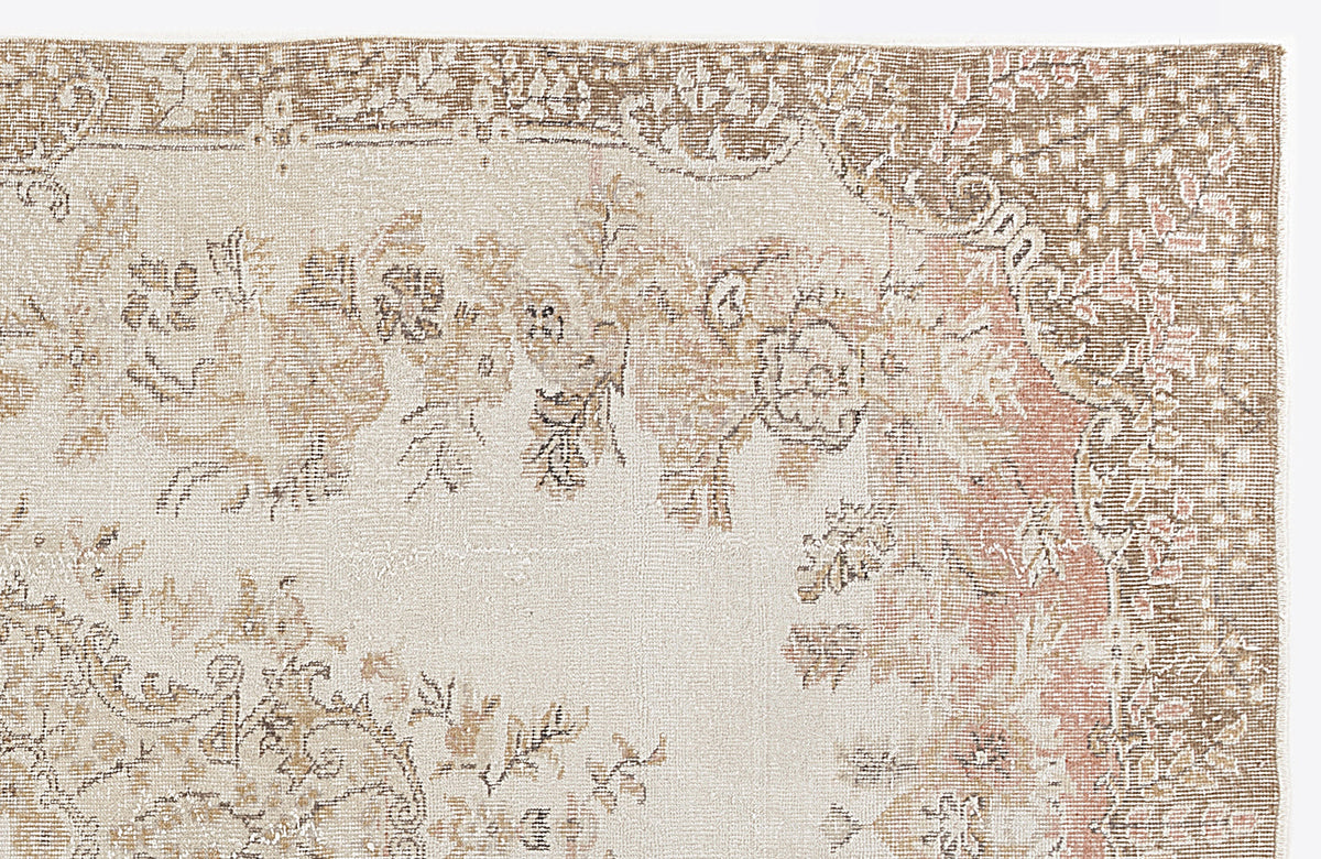 Beige and brown vintage-style rug with a faded floral medallion pattern and a distressed border.
