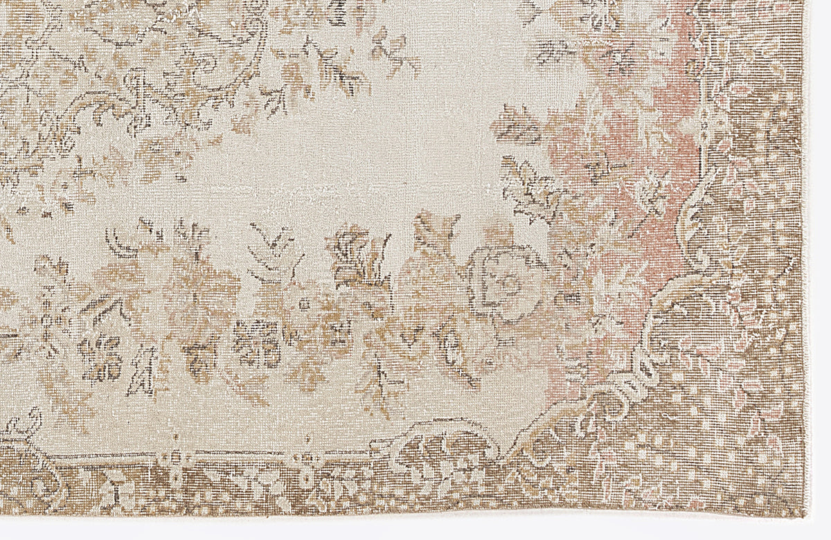 Cream, beige, and muted pink rug with a distressed traditional floral medallion pattern.