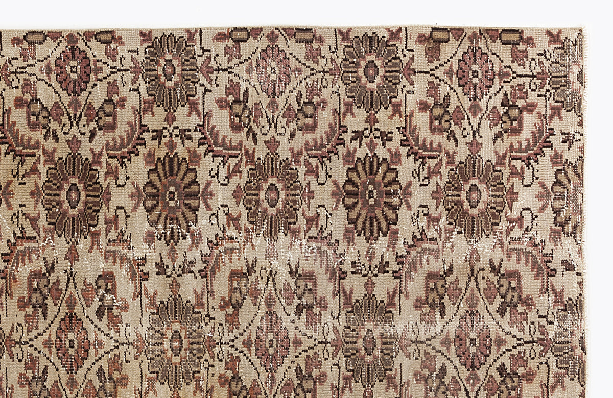 Beige rug with a repeating floral medallion pattern in muted brown and dusty rose, featuring a distressed texture.