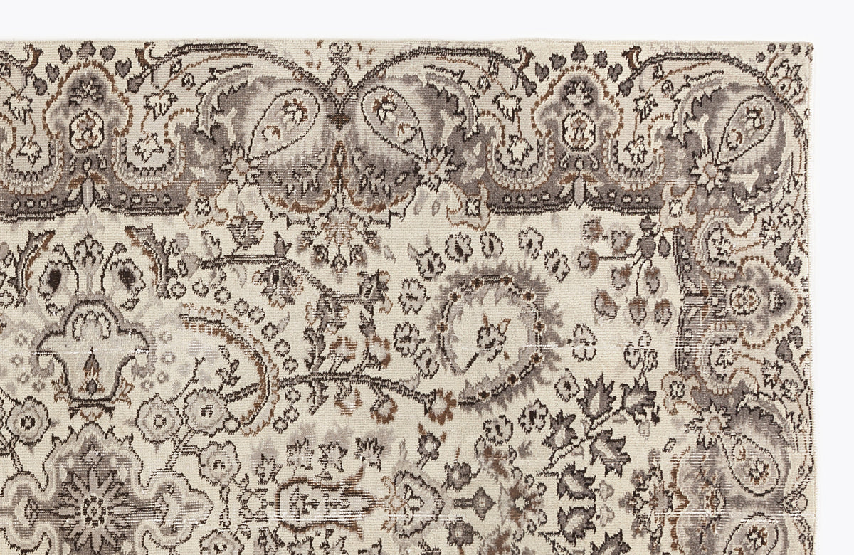 Cream, grey, and brown traditional rug with an intricate floral paisley pattern and a decorative border.