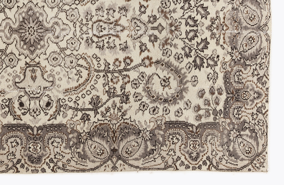 Cream, grey, and brown traditional rug with a distressed, intricate floral medallion and paisley pattern.