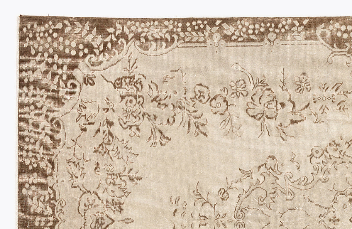 Beige and brown rug with a traditional floral border and central botanical motif on a white background.