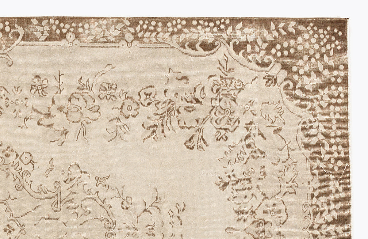 Beige and brown rug with a traditional floral border and central botanical motif on a white background.