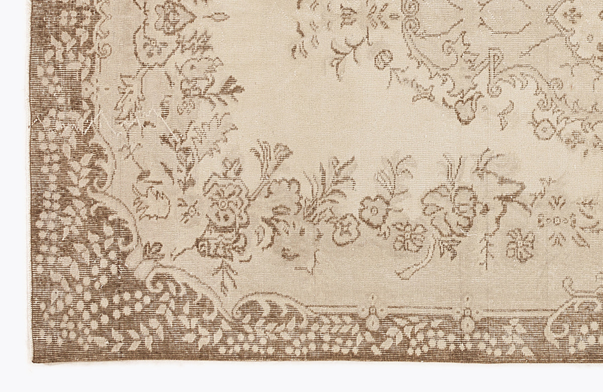 Beige and brown rug with a distressed floral medallion pattern and a detailed botanical border.