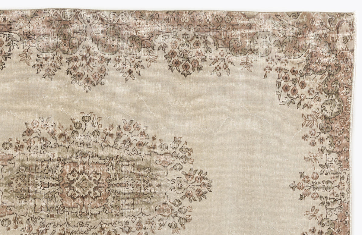 Beige vintage-style rug with a faded floral medallion pattern in muted brown, sage green, and dusty rose tones.