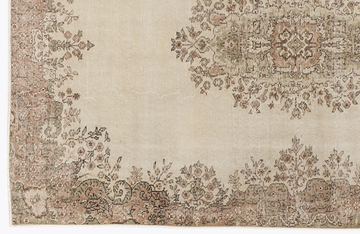 Beige rug with a faded floral medallion and border in muted terracotta and sage green.