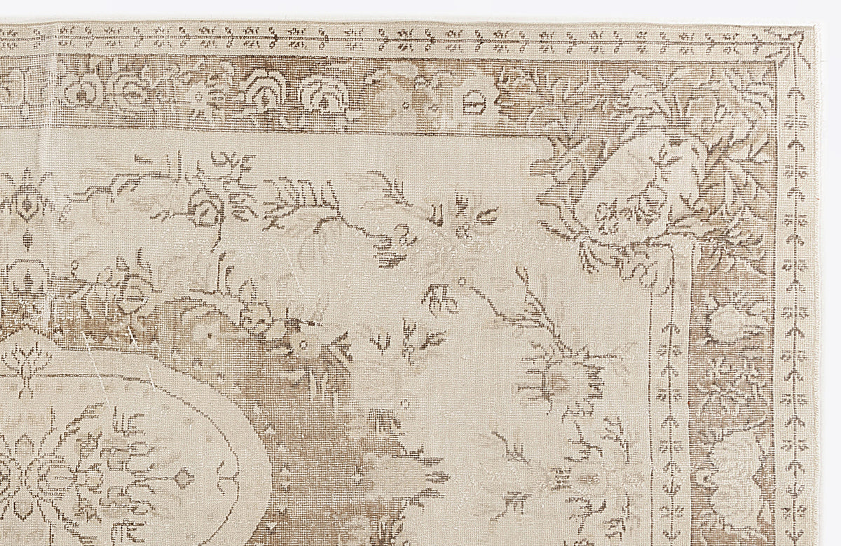 Beige and taupe traditional rug with a distressed floral medallion pattern and ornate border.