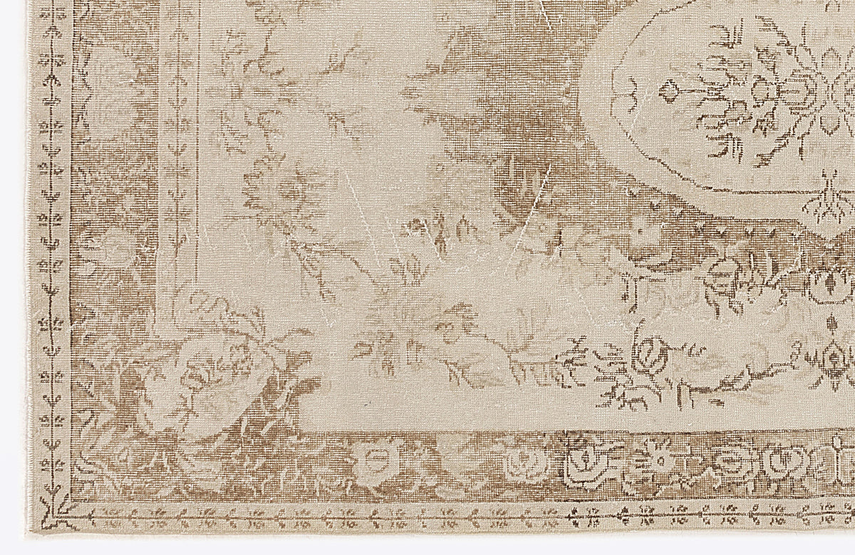 Beige and taupe traditional rug with a distressed floral medallion pattern and a detailed geometric border.