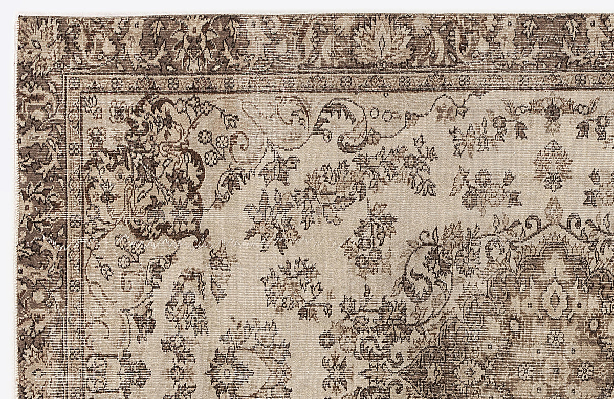 Beige and dark brown traditional rug with a distressed floral medallion pattern and ornate border.