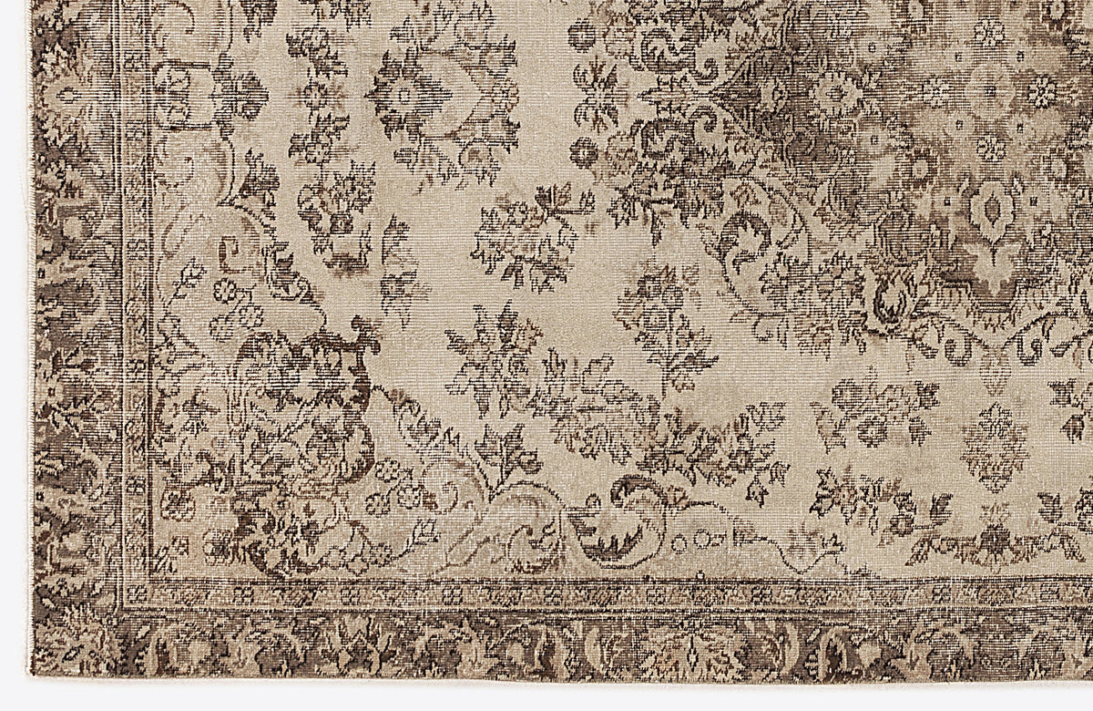 Beige and brown rug with a distressed traditional floral medallion pattern and a detailed border.