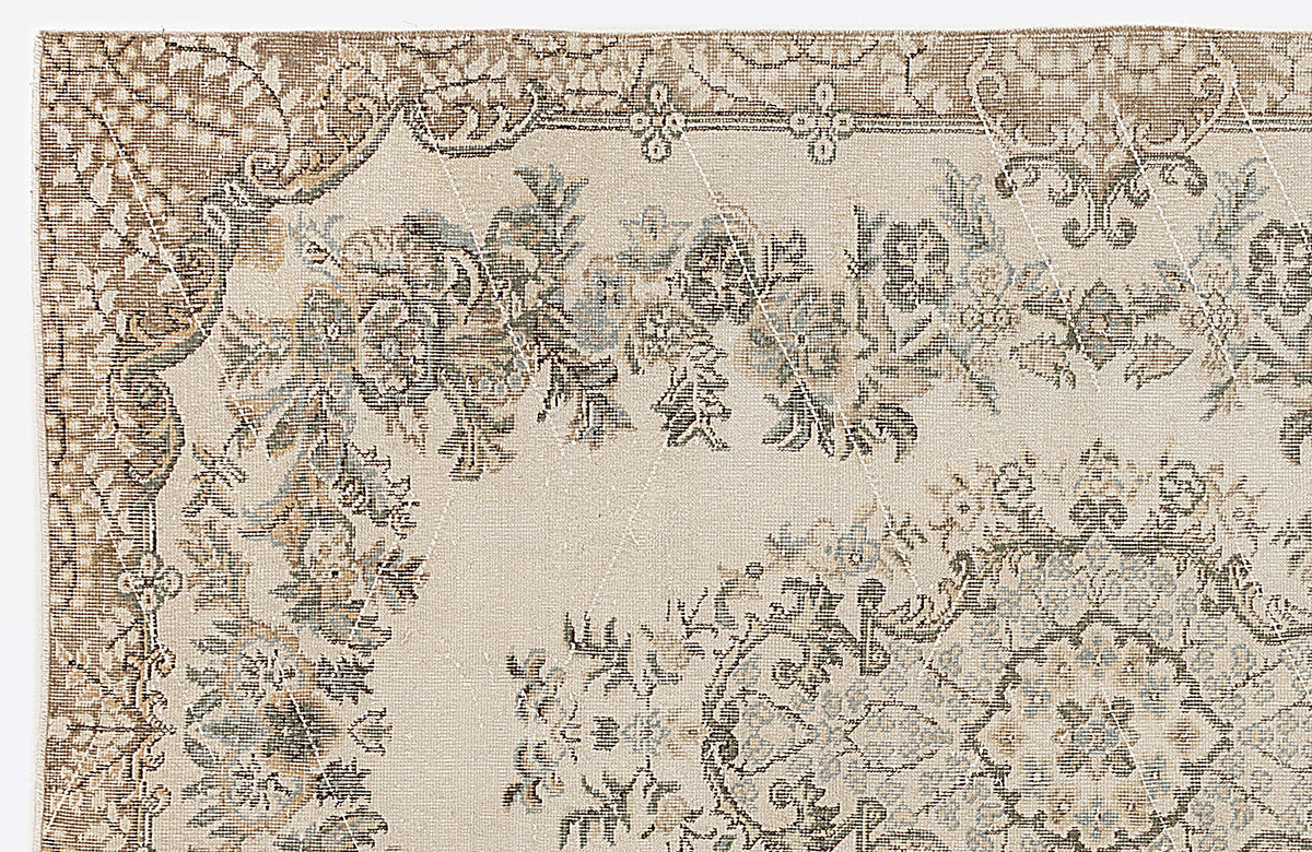 Beige and cream traditional rug with a distressed floral medallion pattern and muted blue and brown accents.