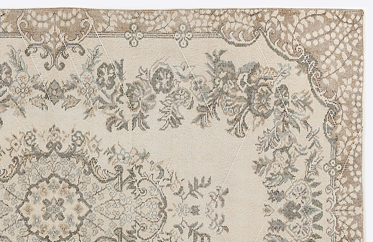 Beige and taupe traditional rug with a distressed floral medallion pattern and a subtle white geometric grid overlay.