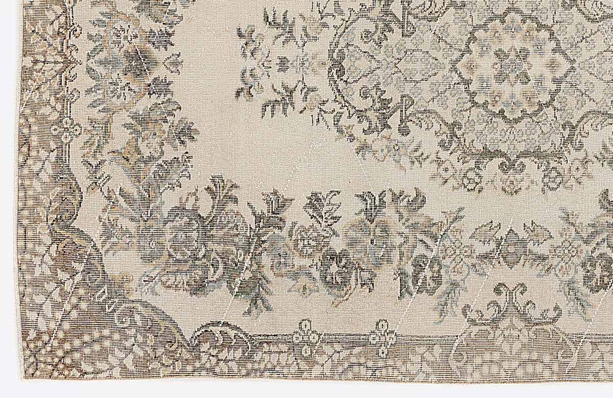 Beige rug with a distressed traditional floral medallion pattern in muted brown, grey, and blue tones.