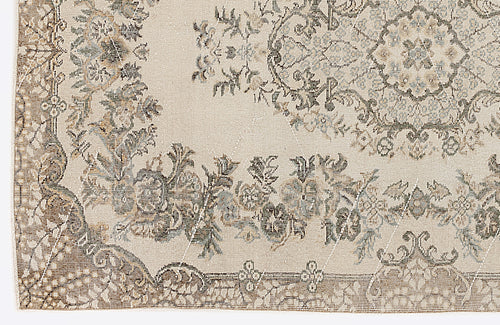 Load image 1 in gallery view. Beige rug with a distressed traditional floral medallion pattern in muted brown, grey, and blue tones.