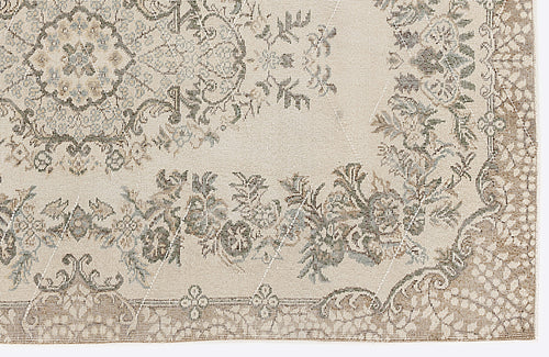 Load image 1 in gallery view. Beige rug with a distressed floral medallion pattern in muted olive, blue, and brown tones on a white background.