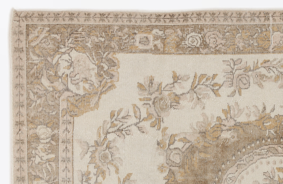 Beige and tan rug with a traditional floral medallion border and vine pattern on a cream field.
