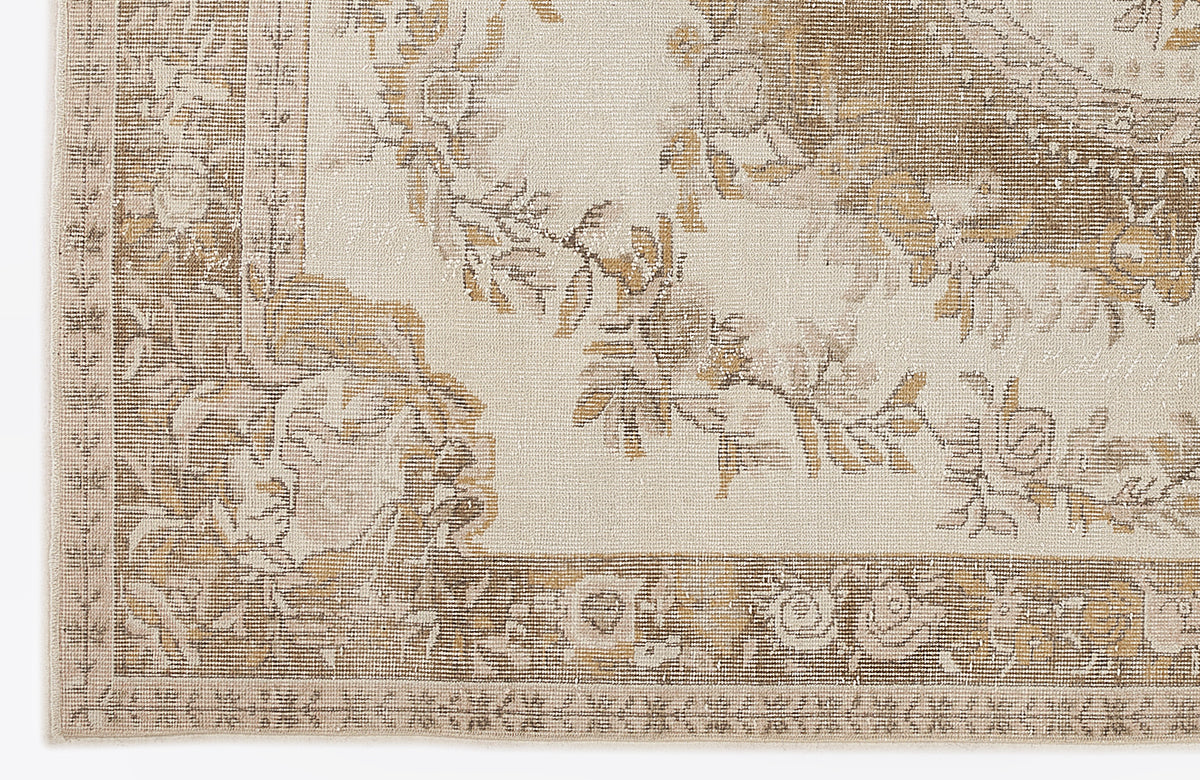 Beige and tan rug with a distressed floral medallion pattern and a decorative border.