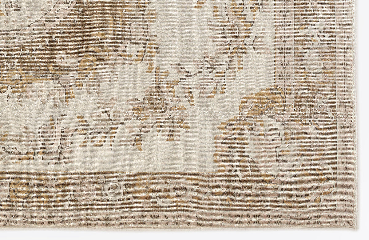 Cream and tan rug with a distressed floral medallion pattern and a decorative border.