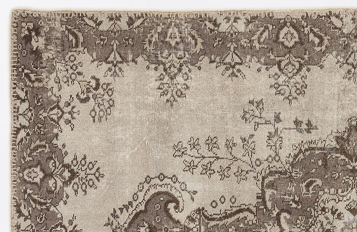 Taupe and beige traditional rug with a distressed, faded floral medallion pattern.