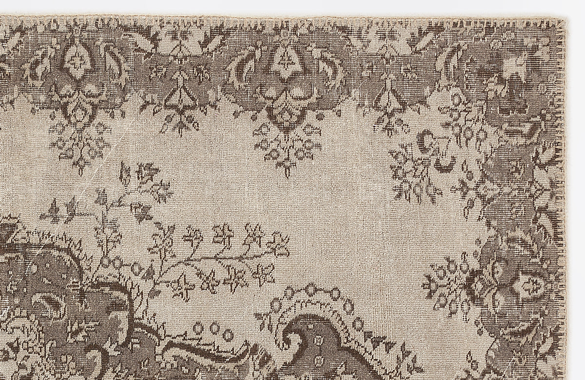Taupe and beige rug with a distressed traditional floral medallion pattern on a white background.