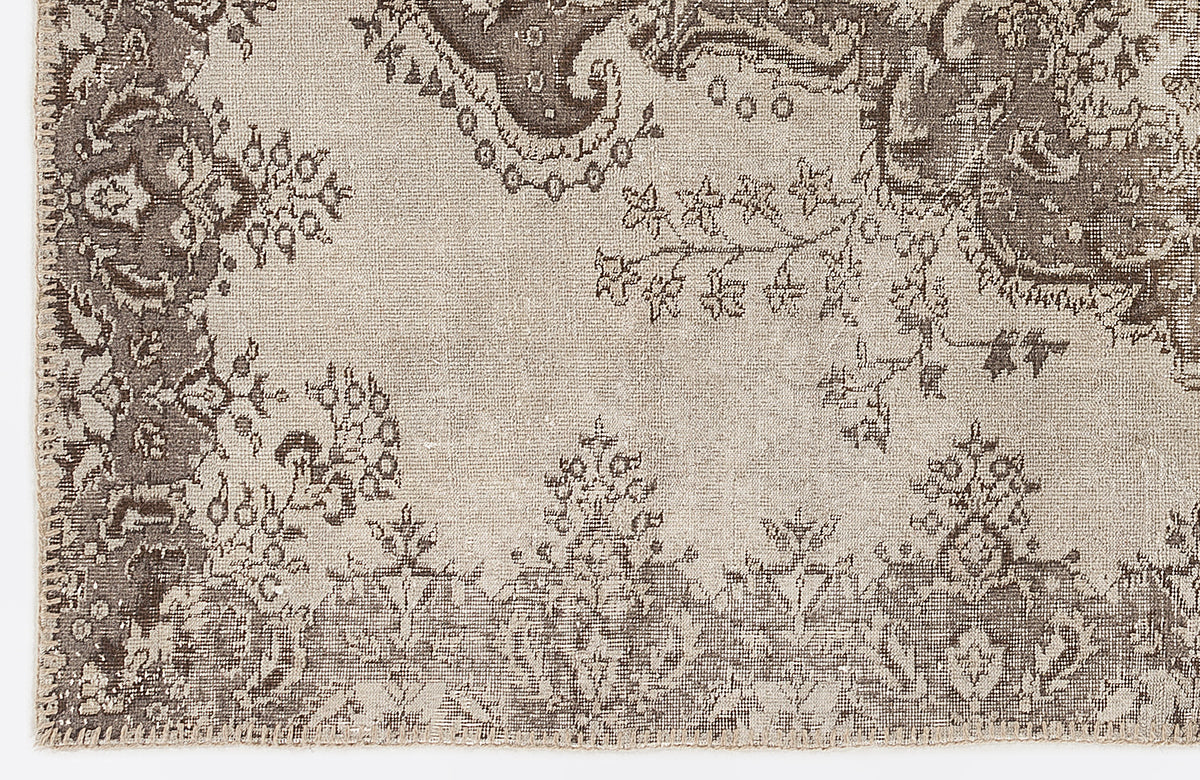 Taupe and beige rug with a distressed traditional floral medallion pattern.