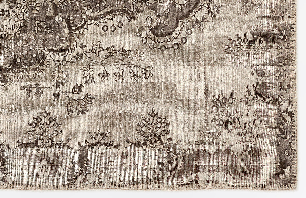 Taupe and dark brown rug with a distressed traditional floral medallion pattern on a white background.