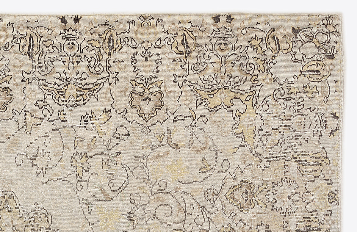 Beige and cream area rug with a distressed, traditional floral medallion pattern in charcoal and muted gold.