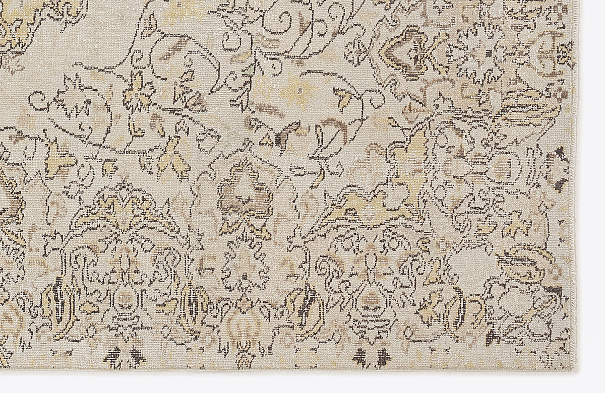Beige and cream area rug with a distressed, traditional floral medallion pattern in charcoal and muted gold.