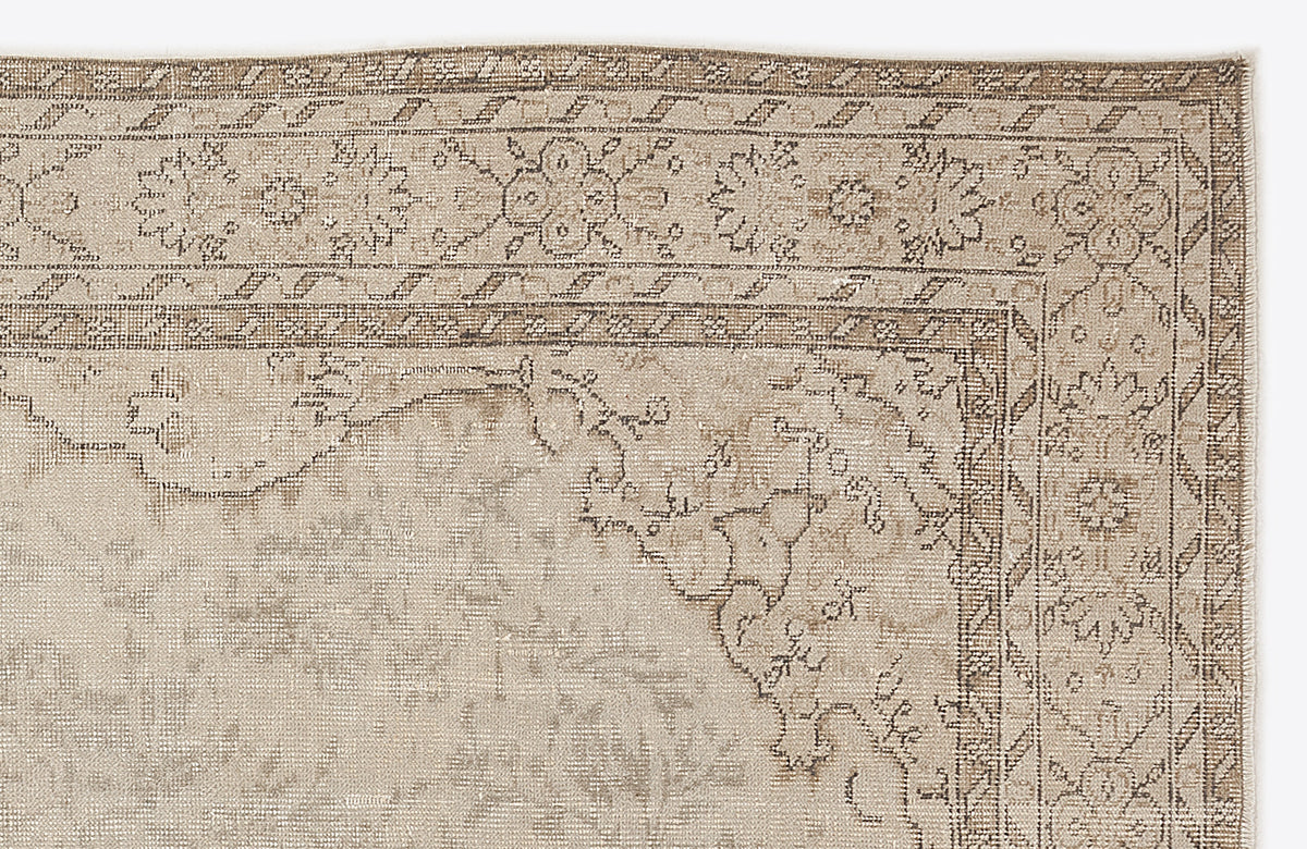 Beige and taupe vintage-style rug with a distressed floral medallion border and geometric corner detail.