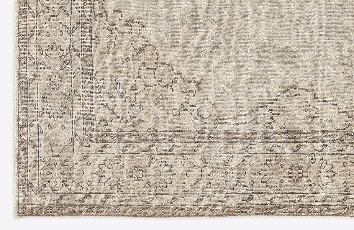 Beige and taupe rug with a distressed traditional floral medallion pattern and a geometric border.