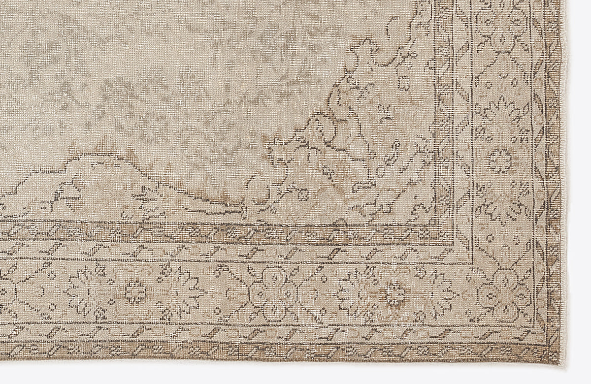 Beige and taupe distressed rug with a traditional floral medallion border and faded central pattern.