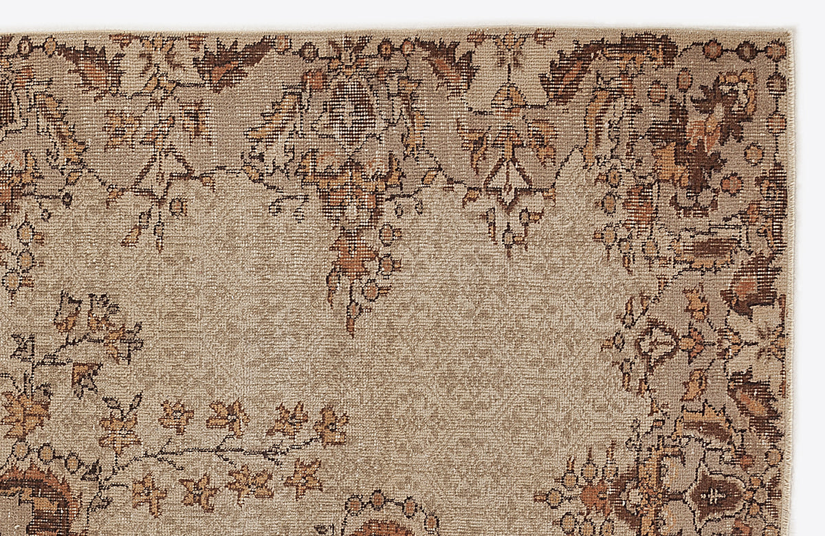 Tan and brown distressed rug with a traditional floral medallion border pattern on a plain background.