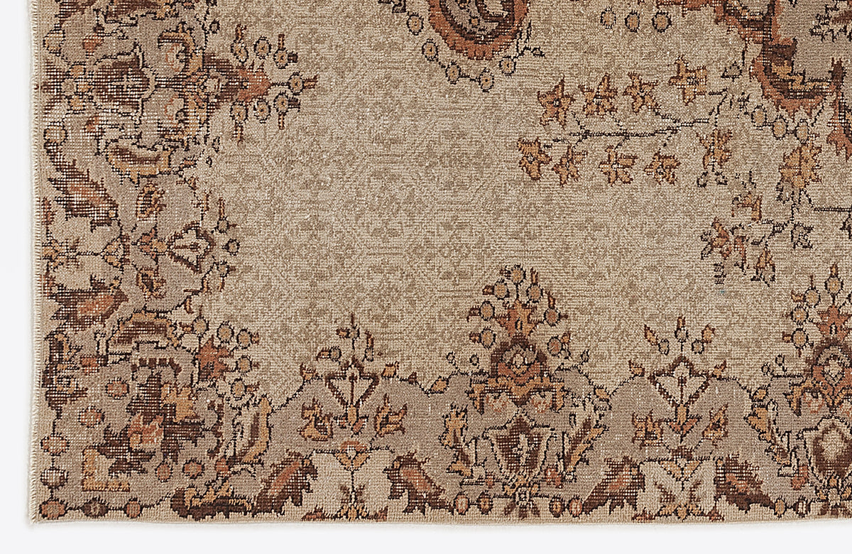 Tan and brown traditional rug with a distressed floral medallion pattern on a white background.