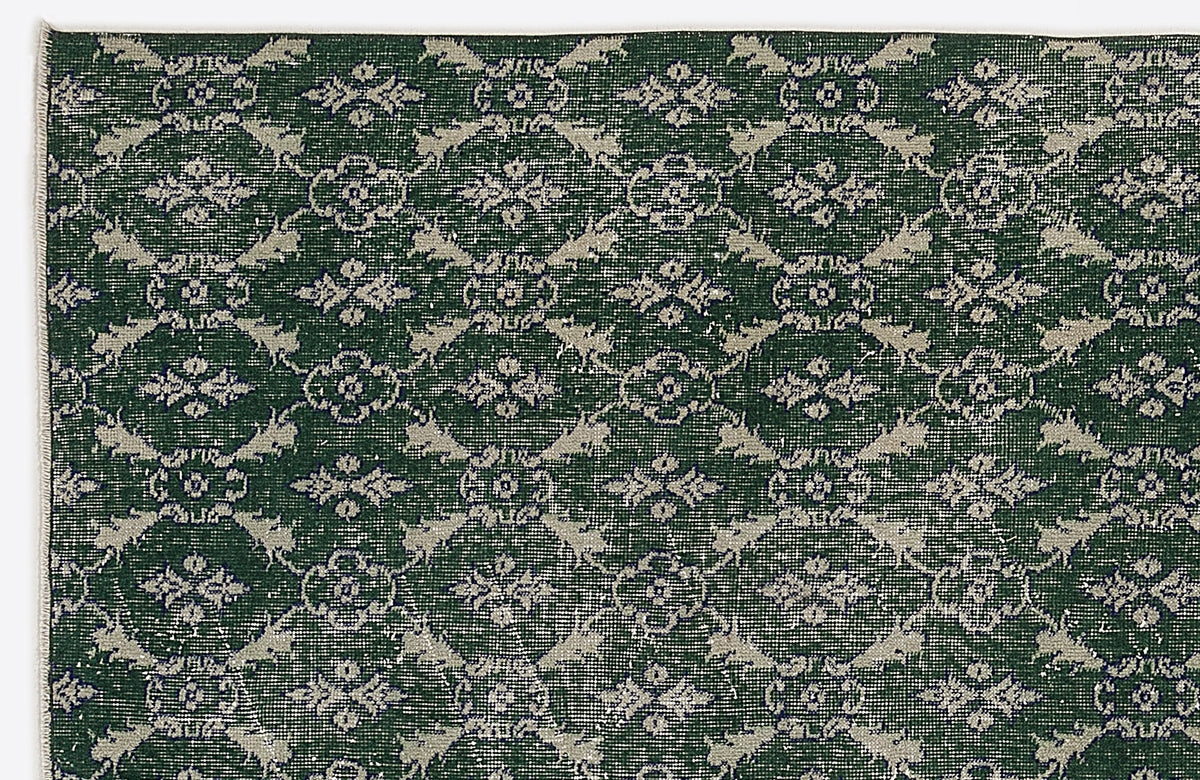 Dark green rug with a repeating light grey floral medallion and lattice pattern.