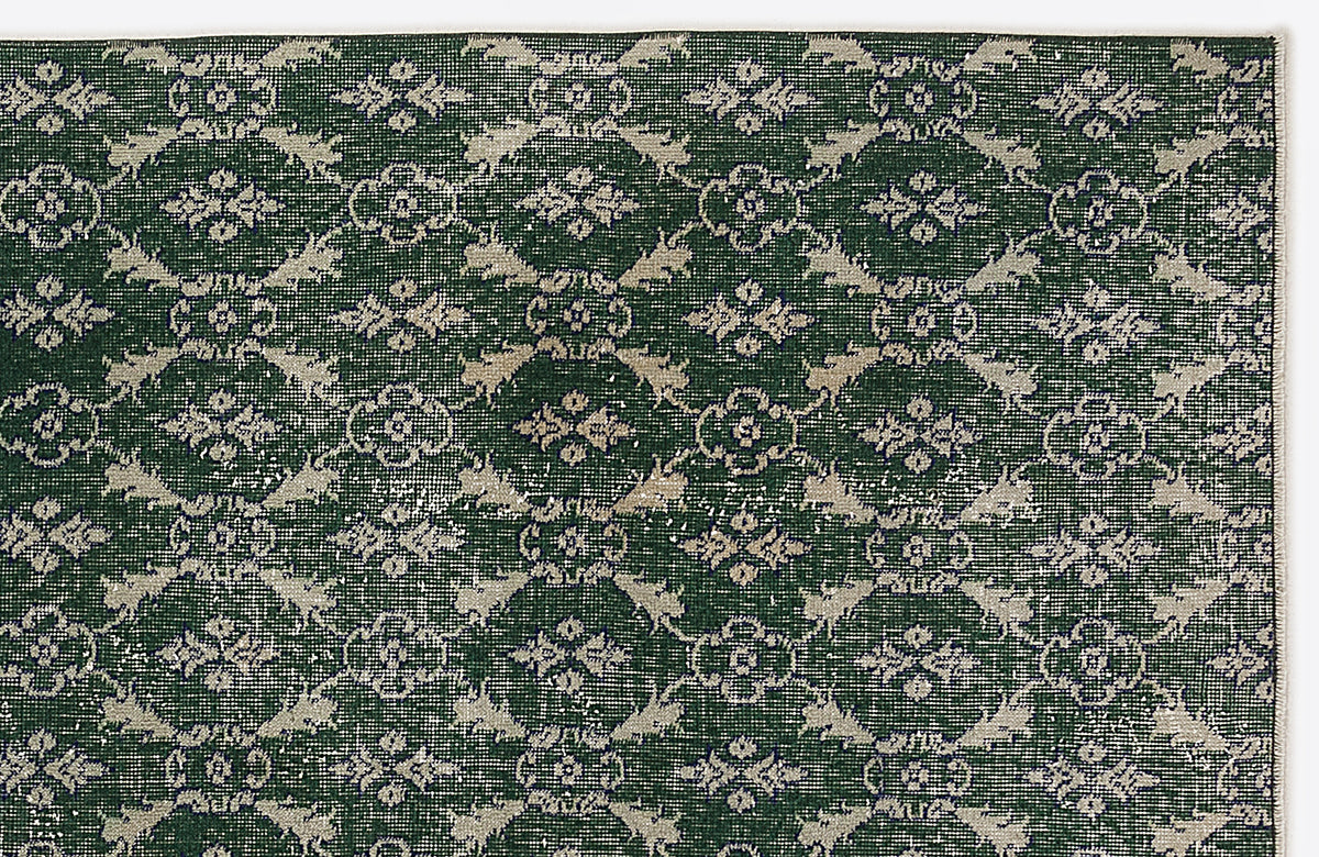 Dark green rug with a repeating beige floral medallion pattern and distressed texture on a white background.