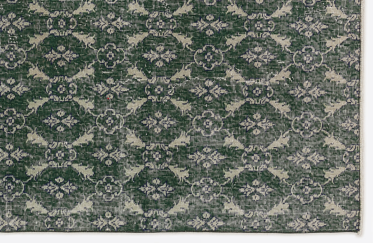 Dark green rug with a repeating cream-colored floral medallion and lattice pattern.