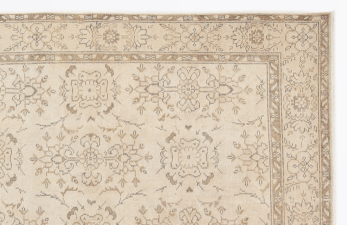 Beige and taupe traditional rug with a distressed floral medallion pattern and a detailed geometric border.