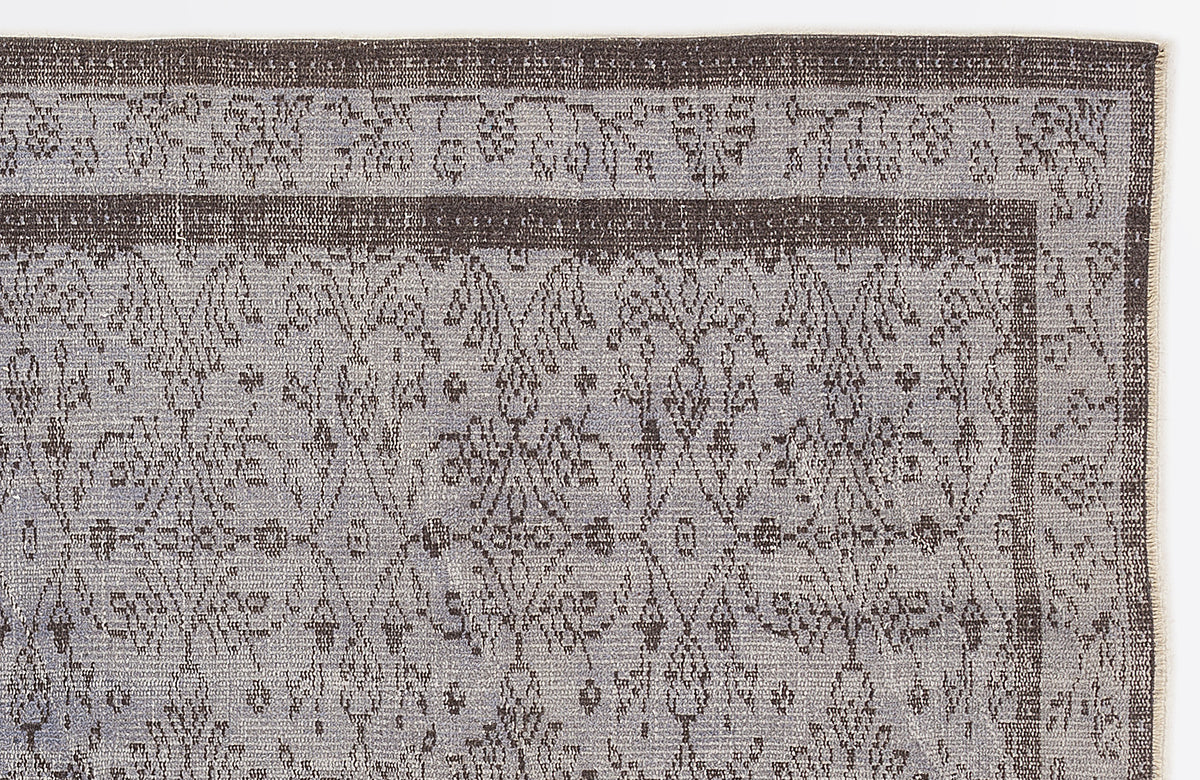 Charcoal and light gray rug with a distressed traditional floral medallion pattern and a bordered edge.