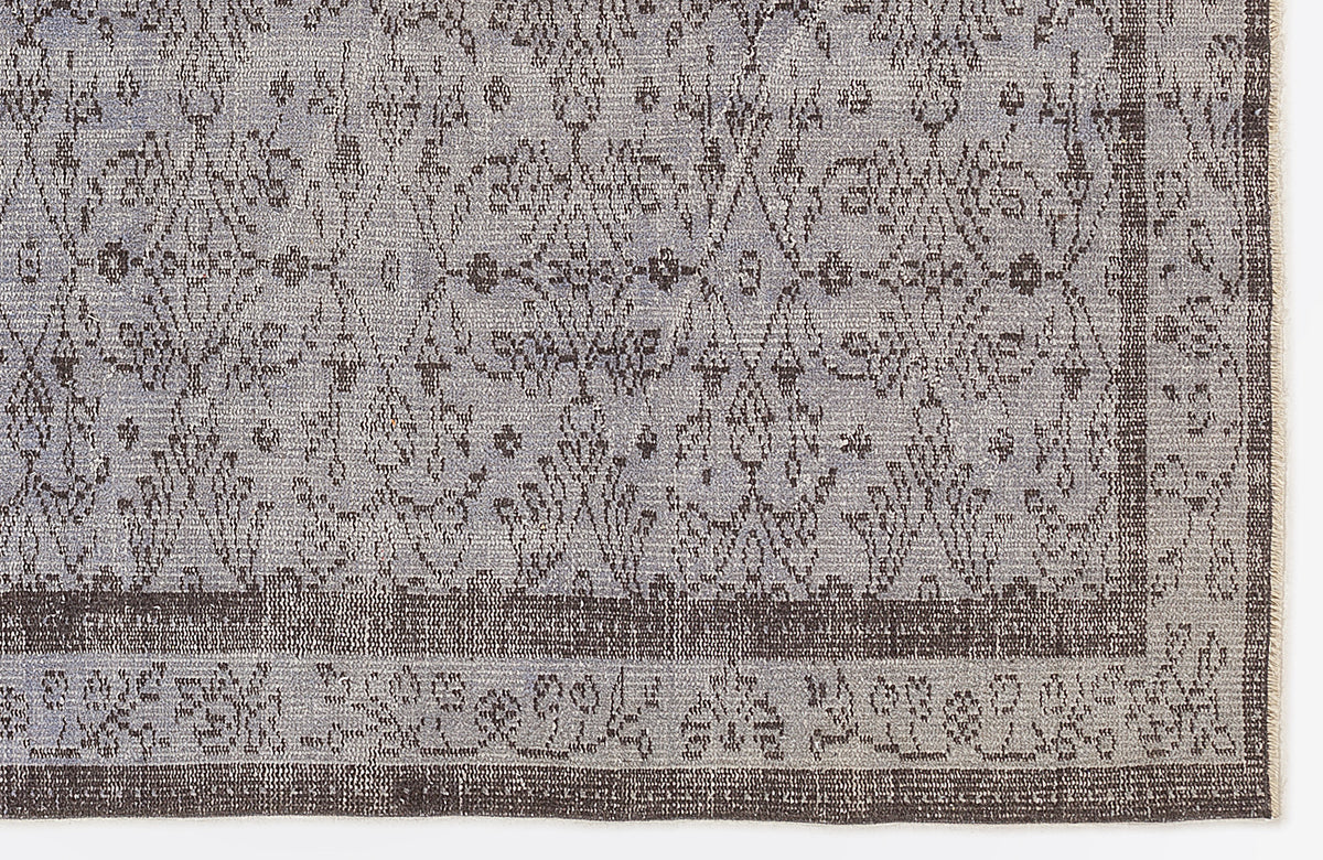 Grey and charcoal rug with a distressed traditional floral medallion pattern and a wide decorative border.