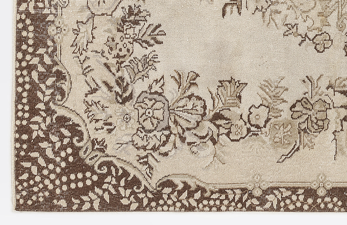 Beige and brown rug with a traditional floral medallion pattern and a dense, dotted border.