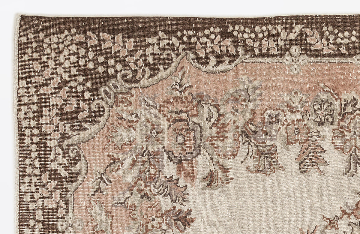 Distressed brown, dusty rose, and cream rug with a traditional floral medallion border and ornate botanical motifs.