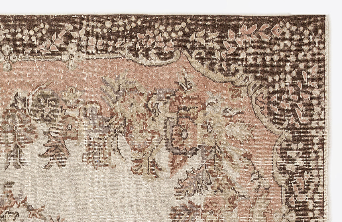 Brown and dusty pink vintage-style rug with a floral medallion pattern and distressed texture on a white background.
