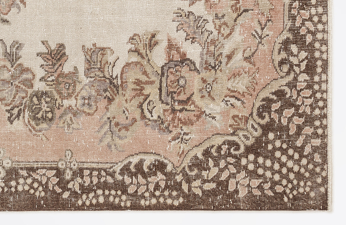Distressed beige and brown rug with a floral medallion pattern and a detailed botanical border.